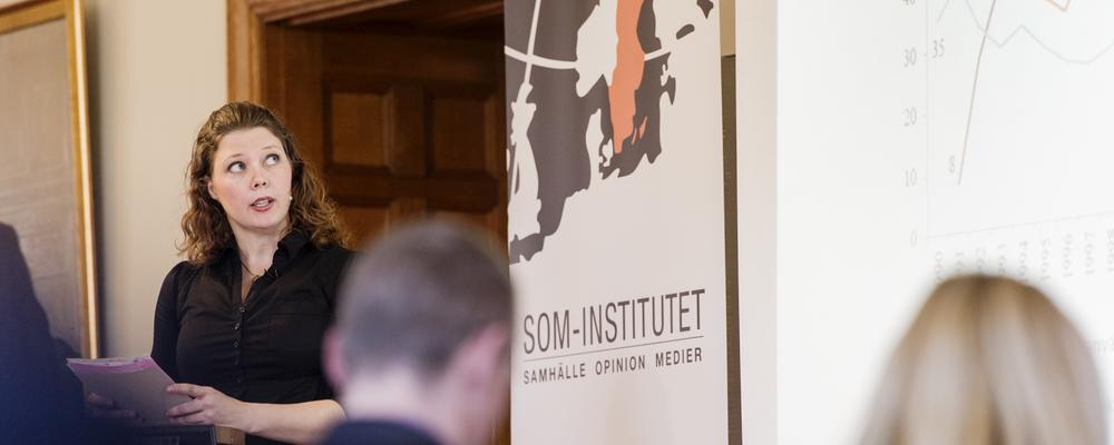 Foto av en kvinlig forskare som presenterar med publik i förgrunden